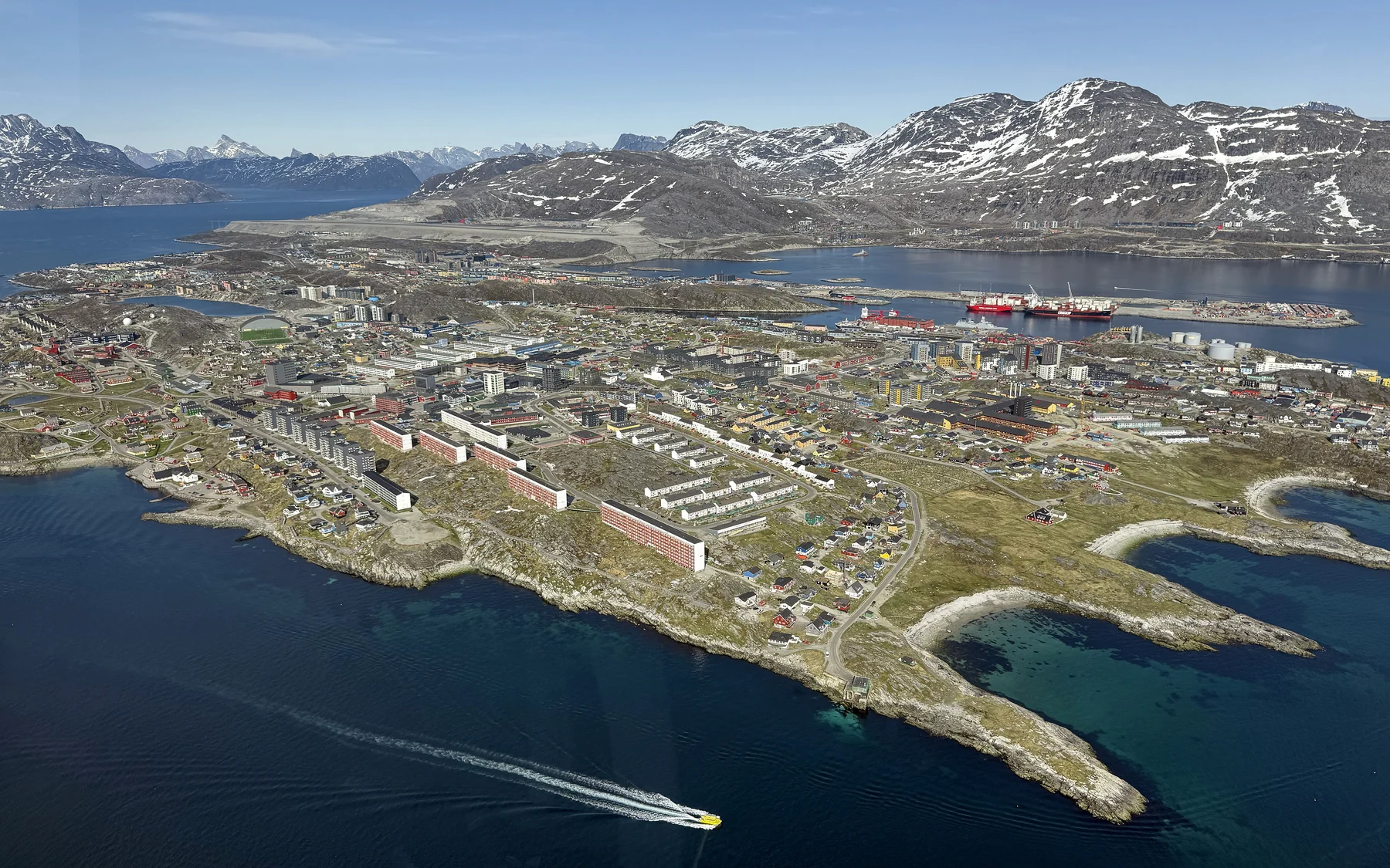 Downtown Nuuk and its rocky coastline surrounded by fjord water, seen from the air